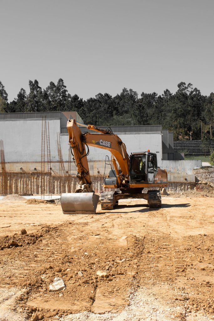 Ein orangefarbener Bagger bei der Arbeit auf einer Baustelle mit Erdboden.